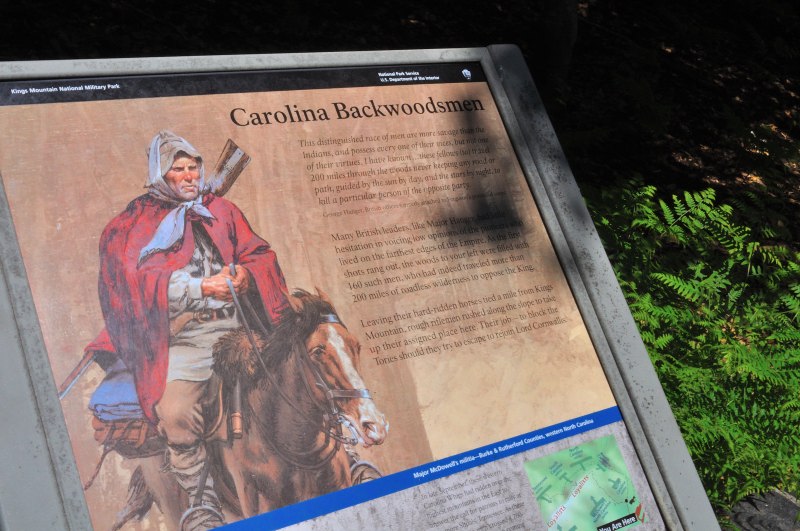 Interpretive sign titled 'Carolina Backwoodsmen' at Kings Mountain National Military Park, featuring an illustration of a rugged frontier fighter on horseback with rifle in hand, alongside text describing the role of backwoodsmen in the Revolutionary War.
