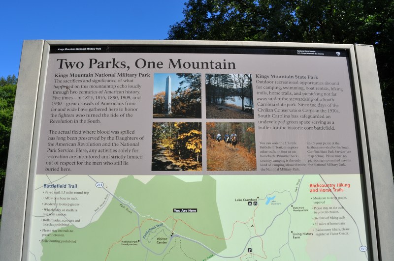 Informational sign titled 'Two Parks, One Mountain' at Kings Mountain, explaining the historical preservation of the National Military Park and the recreational opportunities at the adjoining State Park, with maps and photos for orientation.